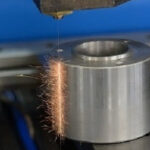 A CNC wire cut machine cutting through a metal plate with precision at https://laserwaterjetindia.com/